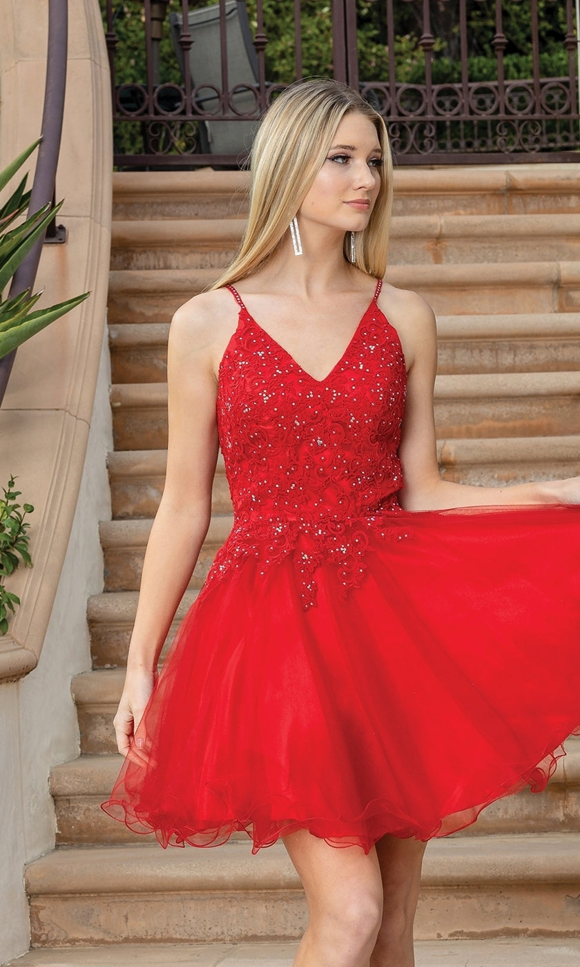 A woman wearing the Lace-Up Short Babydoll Homecoming Dress 3303 with red sequins and a corset bodice stands on outdoor steps, holding her skirt.